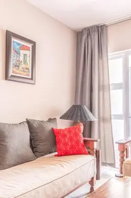 a living room with a couch with a red pillow at NO loadshedding 3km to Gautrain Short or Long stays Uncapped Wi-Fi in Centurion