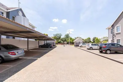 a parking lot with cars parked next to a building at NO loadshedding 3km to Gautrain Short or Long stays Uncapped Wi-Fi in Centurion