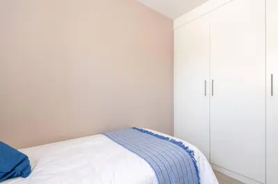 a white bedroom with a bed and white cabinets at NO loadshedding 3km to Gautrain Short or Long stays Uncapped Wi-Fi in Centurion