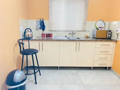 a kitchen with a counter with a sink and a stool at Muzee Wethu Accommodations in Armburg