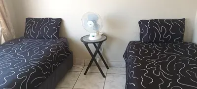 a bedroom with two beds and a table with a fan at 15 Rottweiler Contractors Self-Catering in Pretoria