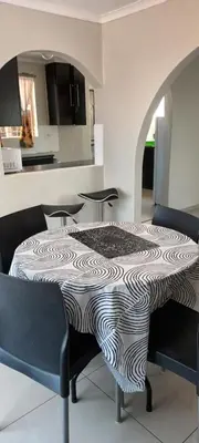 a room with a table with chairs and a kitchen at 15 Rottweiler Contractors Self-Catering in Pretoria