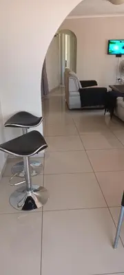 a room with two chairs and a couch and a tv at 15 Rottweiler Contractors Self-Catering in Pretoria