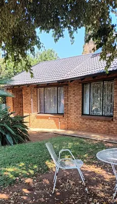 a chair sitting in the grass in front of a house at 15 Rottweiler Contractors Self-Catering in Pretoria