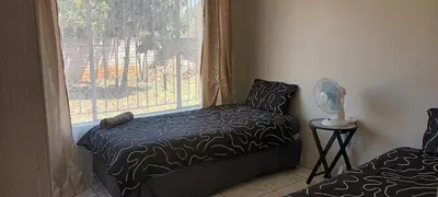 a bedroom with a bed and a window with a fan at 15 Rottweiler Contractors Self-Catering in Pretoria