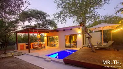 a house with a swimming pool and a wooden deck at The Suite Luxury Safari Villa, Close to KNP, Starbed, Giraffe-Feeding-Tower, Bush-Bath in Marloth Park