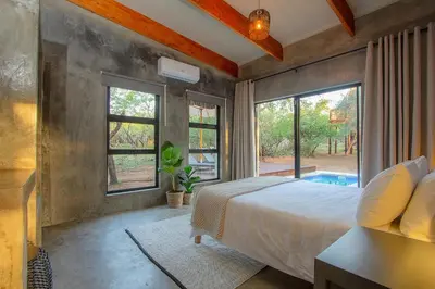a bedroom with a bed and a large window at The Suite Luxury Safari Villa, Close to KNP, Starbed, Giraffe-Feeding-Tower, Bush-Bath in Marloth Park