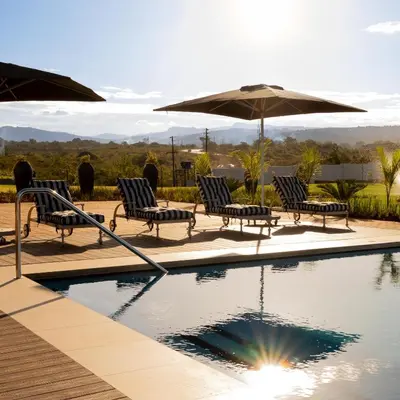 a swimming pool with chairs and an umbrella at Premier Hotel Thohoyandou in Thohoyandou