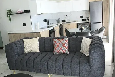 a living room with a couch in front of a kitchen at The Blyde in Pretoria