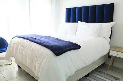 a bedroom with a large bed with a blue headboard at The Blyde in Pretoria