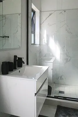 a white bathroom with a sink and a shower at The Blyde in Pretoria