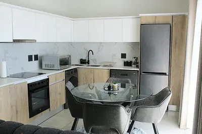 a kitchen with a glass table with chairs in it at The Blyde in Pretoria
