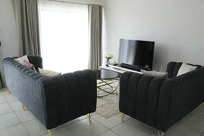 a living room with two couches and a tv at The Blyde in Pretoria