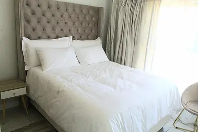 a bedroom with a white bed with a large window at The Blyde in Pretoria