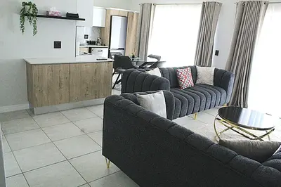 a living room with two couches and a kitchen at The Blyde in Pretoria