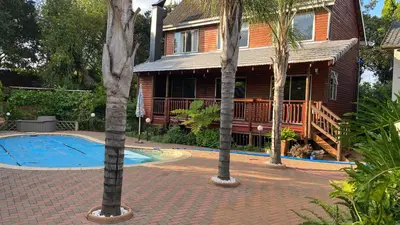 a house with a swimming pool in front of a house at Cozy Wood Retreat in Centurion