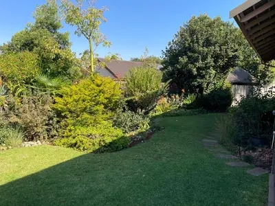 a garden with green grass and bushes and trees at Cozy Wood Retreat in Centurion