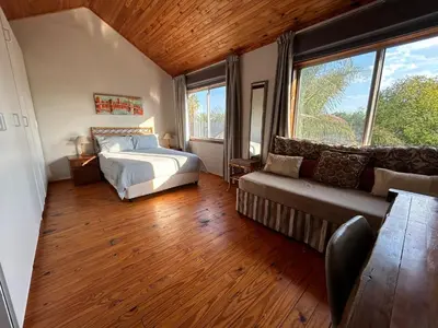 a bedroom with a bed and a couch and windows at Cozy Wood Retreat in Centurion