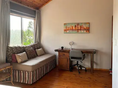 a living room with a couch and a desk and a window at Cozy Wood Retreat in Centurion