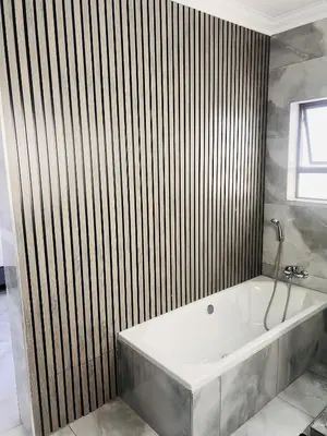 a bath tub in a bathroom with a wooden wall at Zindiza Guesthouse 2 in Witbank