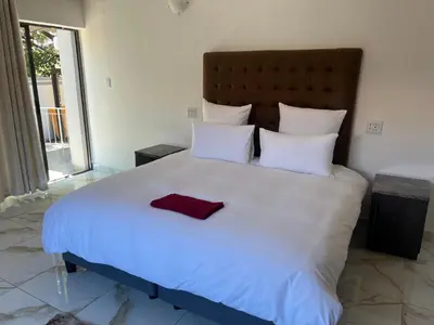 a large white bed with a red towel on it at Zindiza Guesthouse 2 in Witbank