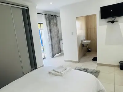 a bedroom with a white bed and a bathroom at Zindiza Guesthouse 2 in Witbank