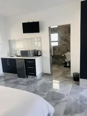 a white kitchen with a sink and a bathroom at Zindiza Guesthouse 2 in Witbank