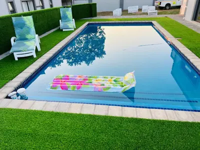 a swimming pool with a chair and a lawn at Zindiza Guesthouse 2 in Witbank