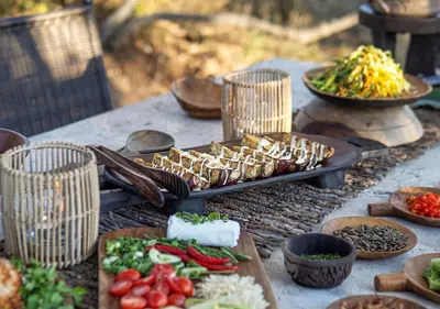 a table with plates of food and bowls of vegetables at Motswari African Retreat & Walking Safaris by NEWMARK in Timbavati Game Reserve