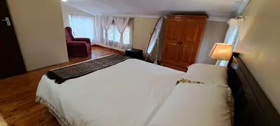 a bedroom with a large white bed and a chair at Die Boma Eenheid in Rayton