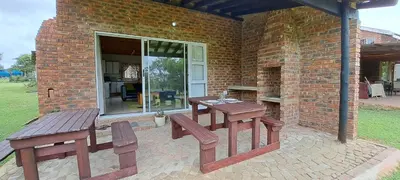 a patio with two benches and a table and a brick wall at Die Boma Eenheid in Rayton