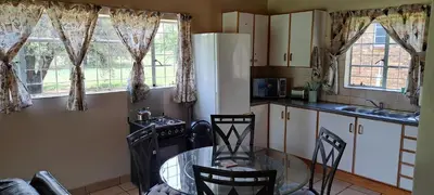 a kitchen with a glass table and chairs and windows at Die Boma Eenheid in Rayton
