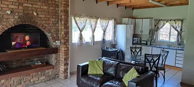 a living room with a couch and a brick fireplace at Die Boma Eenheid in Rayton