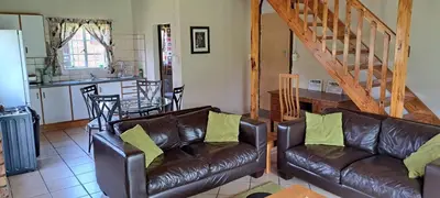 a living room with two leather couches and a kitchen at Die Boma Eenheid in Rayton