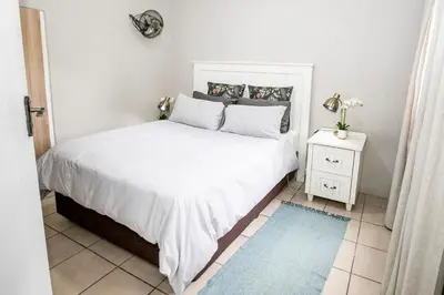 a bedroom with a large white bed and a night stand at Buchan's corner Unit 1 in Hartbeespoort