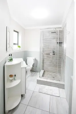 a white bathroom with a shower and a toilet at Buchan's corner Unit 1 in Hartbeespoort