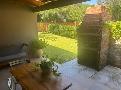 a patio with a fireplace and a wooden table at Buchan's corner Unit 1 in Hartbeespoort