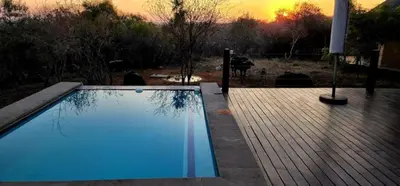 a swimming pool with a sunset in the background at 22 Siyanda Mabalingwe in Mabula