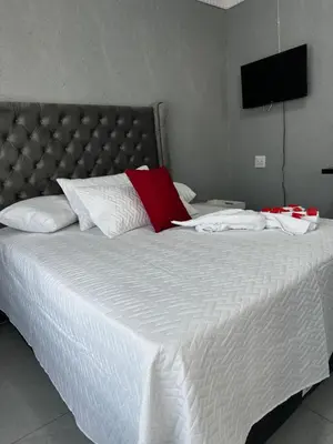 a large white bed with a red pillow on it at RANTI Guest House in Ga-Mothiba