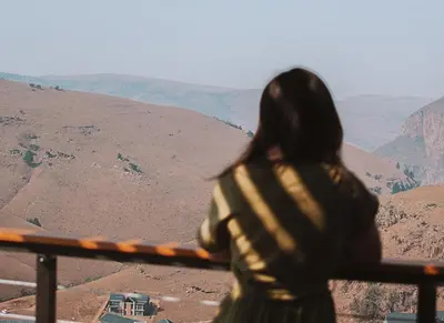 a woman standing on a railing looking out at the mountains at 848 at Highland Gate by Euphoric Leisure in Dullstroom