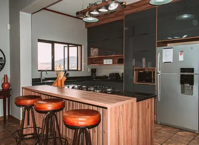 a kitchen with a counter with bar stools and a refrigerator at 848 at Highland Gate by Euphoric Leisure in Dullstroom