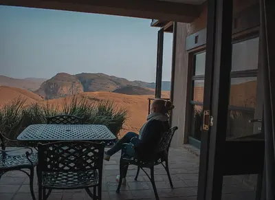 a woman sitting at a table on a patio with a view at 848 at Highland Gate by Euphoric Leisure in Dullstroom