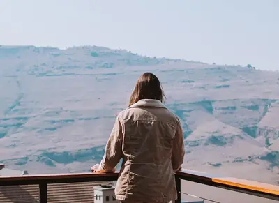 a woman standing on a balcony looking out at the mountains at 848 at Highland Gate by Euphoric Leisure in Dullstroom