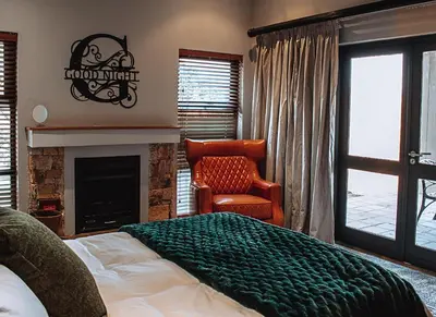 a bedroom with a bed and a chair and a fireplace at 848 at Highland Gate by Euphoric Leisure in Dullstroom