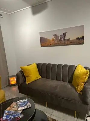 a living room with a brown couch and yellow pillows at Waterfall Paradise Entire Executive 1 Bed Apt in Midrand