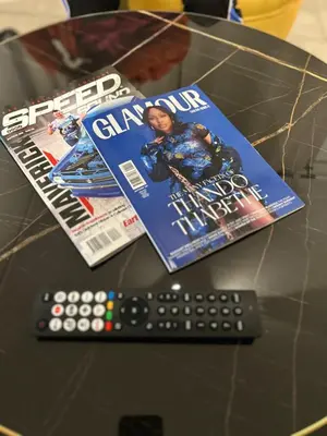 two magazines on a table with a remote control at Waterfall Paradise Entire Executive 1 Bed Apt in Midrand