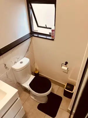 a bathroom with a toilet with a black seat and a window at Waterfall Paradise Entire Executive 1 Bed Apt in Midrand