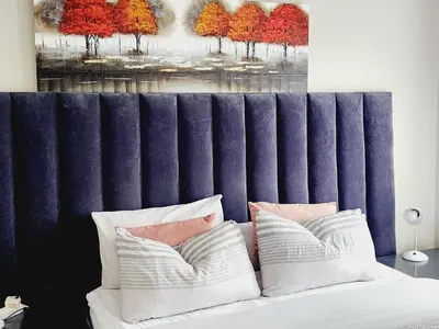 a bed with two pillows and a painting of trees at Lions Haven in Pretoria