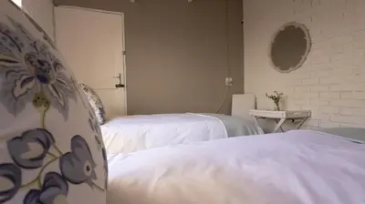 two beds in a room with white sheets at Stay at Percy Self Catering House in Nelspruit