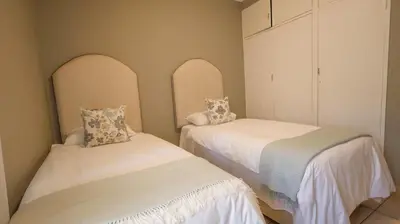 two beds in a room with white walls at Stay at Percy Self Catering House in Nelspruit